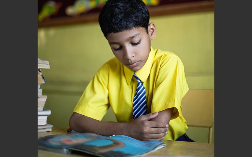 Photo of a boy in a school uniform who is reading