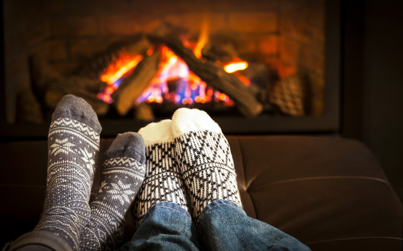 Photo of a couple (of feet) getting warm and snug in front of a fireplace