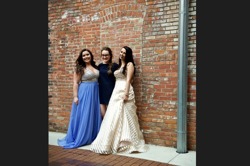 Photo of three girlfriends who are dressed up and ready for the prom