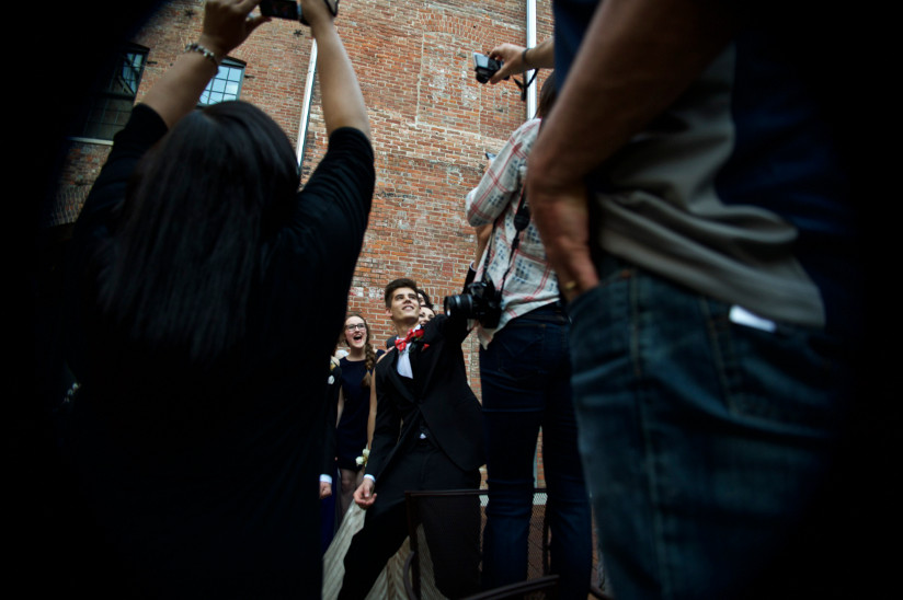 Photo of people taking pictures of teenagers taking a selfie before the prom