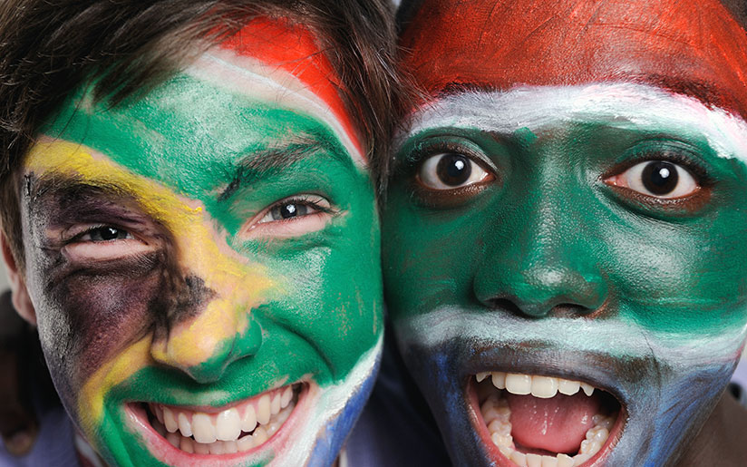 Photo of teenagers of mixed race with South African flags painted on their faces